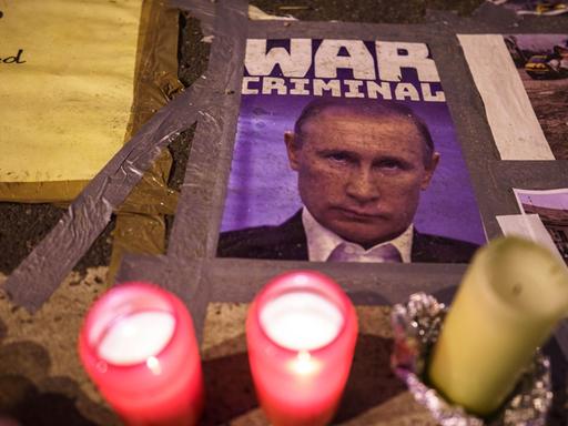 Ukraine-Krieg - Russisches Konsulat in Frankfurt/Main. Kerzen brennen vor einem Bild des russischen Präsidenten Putin, das ihn als «War Criminal» (Kriegsverbrecher) bezeichnet, auf dem Pflaster vor dem russischen Konsulat.