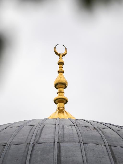 Auf einem Dach einer Moschee ist eine Mondsichel angebracht.