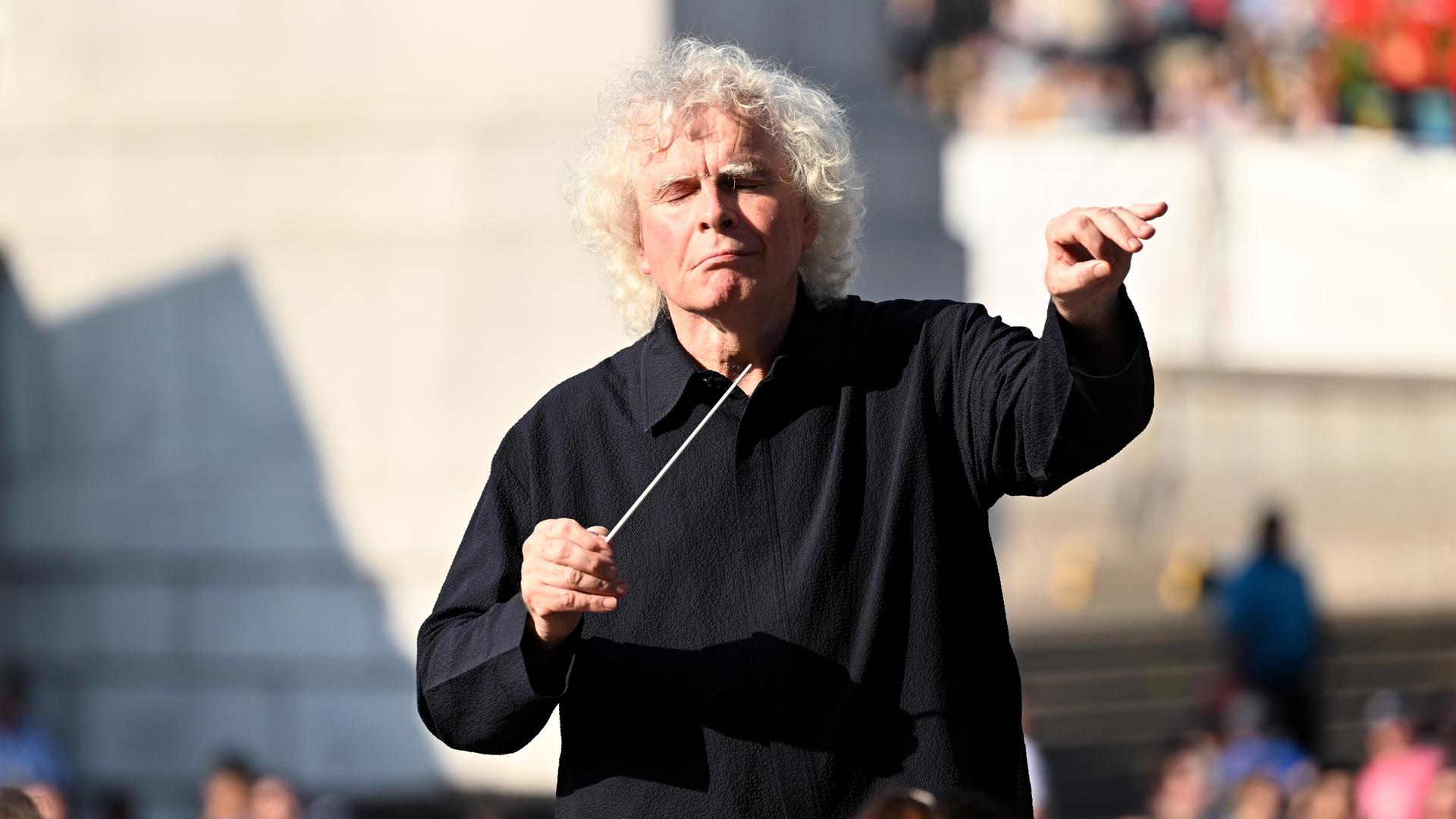 Simon Rattle dirigiert an einem sonnigen Tag Open Air das London Symphony Orchestra in London.