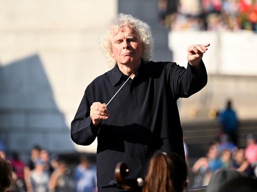 Simon Rattle dirigiert an einem sonnigen Tag Open Air das London Symphony Orchestra in London.