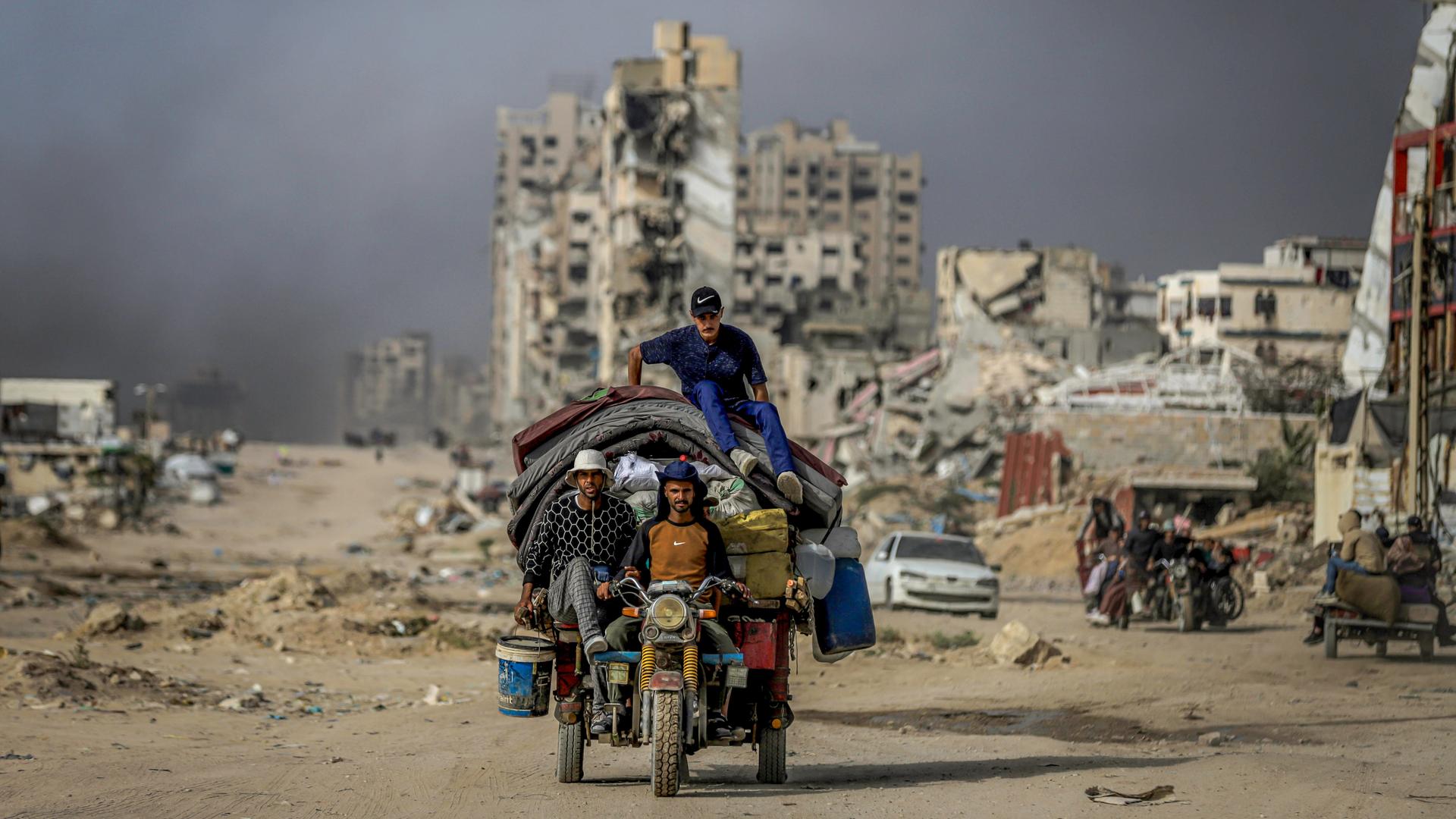 Drei Männer auf einem Motorrad mit überladenem Anhänger in Gaza Drei Männer auf einem Motorrad mit überladenem Anhänger in Gaza