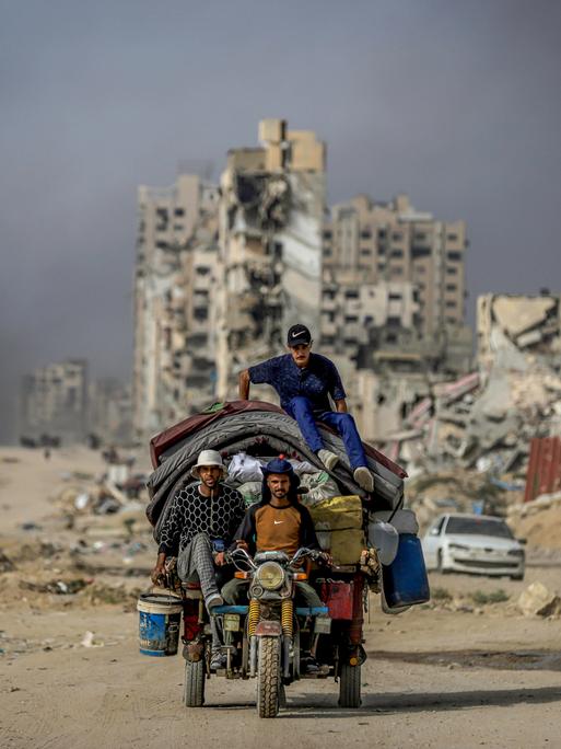 Drei Männer auf einem Motorrad mit überladenem Anhänger in Gaza