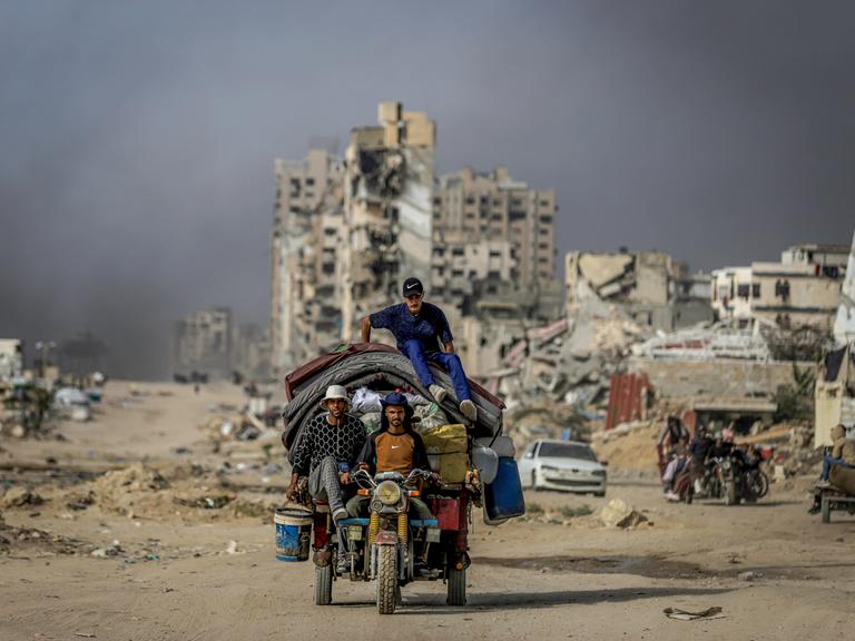 Drei Männer auf einem Motorrad mit überladenem Anhänger in Gaza