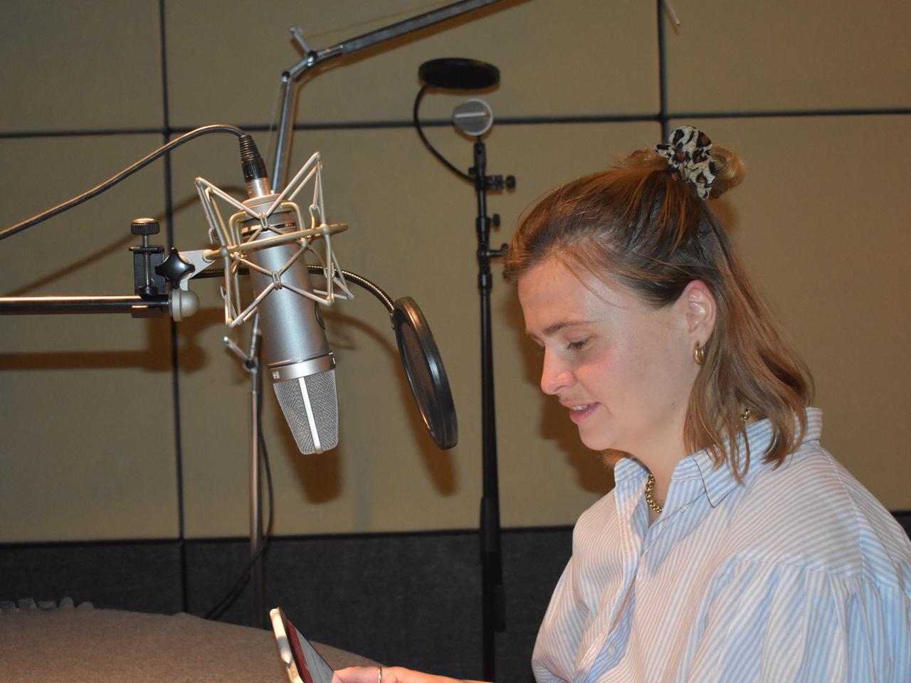 Die Schauspielerin Lisa Hrdina, sitzend vor einem Aufnahmemikrofon.