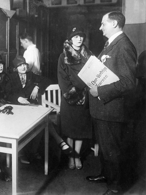 Schauspielerinnen warten im Vorraum, bevor sie vorsprechen dürfen. Ein Mann steht ihnen gegenüber mit einer Mappe unter dem Arm. (Aufnahmedatum: 1926) Schauspielerinnen warten im Vorraum, bevor sie vorsprechen dürfen. Ein Mann steht ihnen gegenüber mit einer Mappe unter dem Arm. (Aufnahmedatum: 1926)