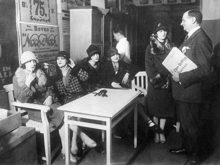 Schauspielerinnen warten im Vorraum, bevor sie vorsprechen dürfen. Ein Mann steht ihnen gegenüber mit einer Mappe unter dem Arm. (Aufnahmedatum: 1926) Schauspielerinnen warten im Vorraum, bevor sie vorsprechen dürfen. Ein Mann steht ihnen gegenüber mit einer Mappe unter dem Arm. (Aufnahmedatum: 1926)