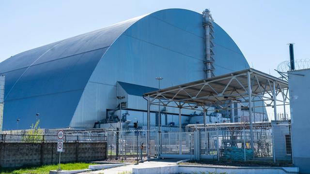 Schutzhülle um den beschädigten Reaktor von dem Atomkraftwerk Tschernobyl in der Ukraine. Die Hülle ist riesengroß und halbkreisförmig. Sie glänzt silbrig.