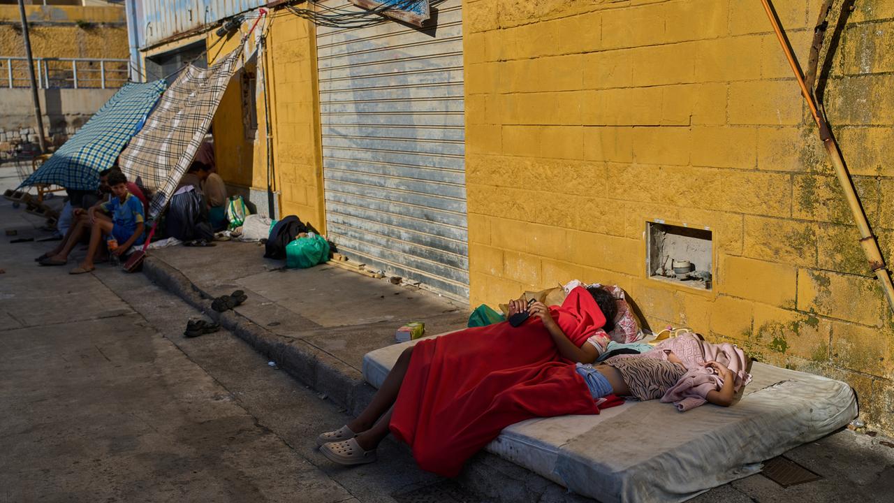 Migranten, die von Marokko nach Spanien eingereist sind, schlafen unter Decken auf der Straße vor einem Lagerhausgelände nahe der spanisch-marokkanischen Grenze in der spanischen Enklave Ceuta. 