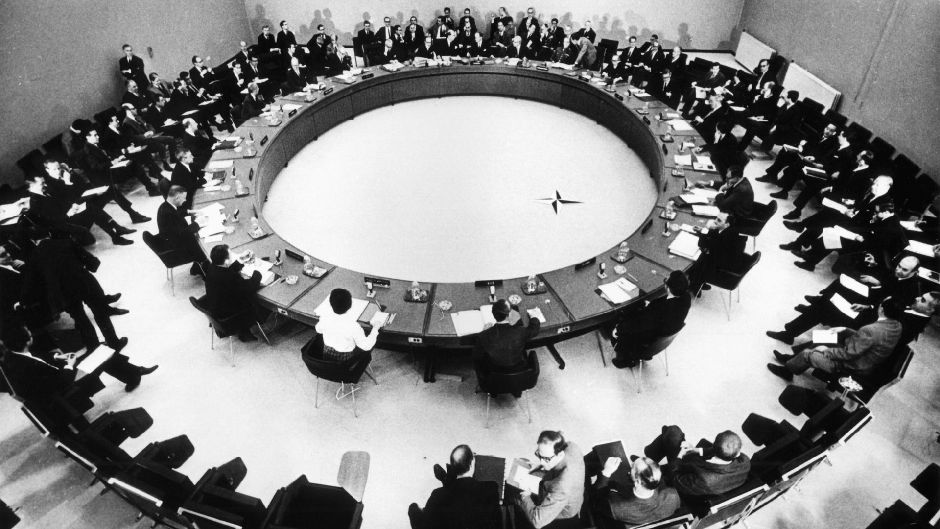 Vertreter der zwölf Nato-Mitgliedsstaaten sitzen 1949 um einen Konferenztisch.