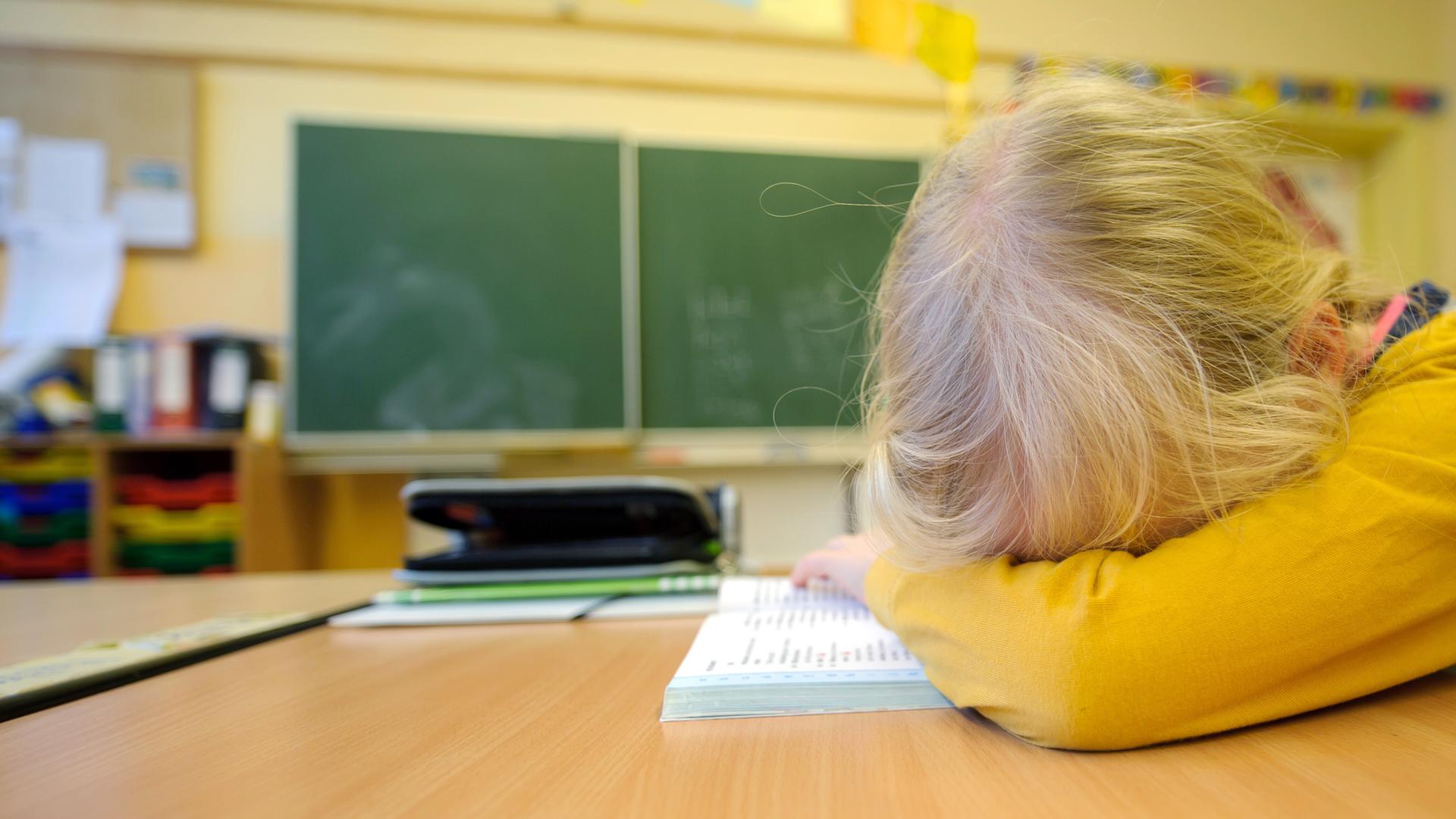Ein Schulkind liegt niedergeschlagen auf seiner Schulbank Ein Schulkind liegt niedergeschlagen auf seiner Schulbank