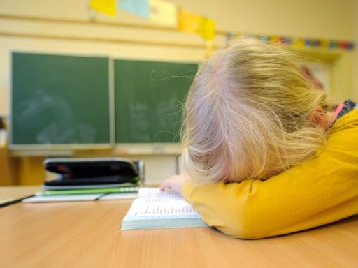 Ein Schulkind liegt niedergeschlagen auf seiner Schulbank Ein Schulkind liegt niedergeschlagen auf seiner Schulbank
