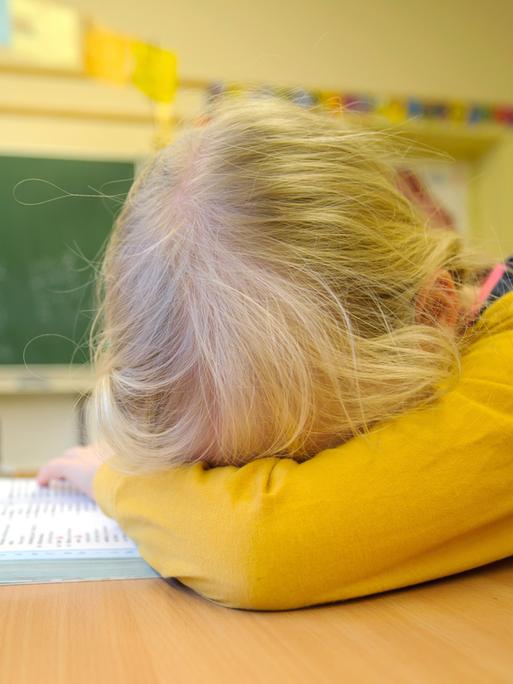 Ein Schulkind liegt niedergeschlagen auf seiner Schulbank Ein Schulkind liegt niedergeschlagen auf seiner Schulbank