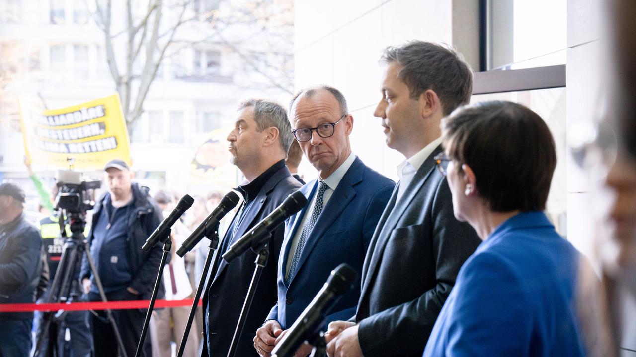 Markus Söder, Friedrich Merz, Lars Klingbeil und Saskia Esken stehen bei einer Pressekonferenz vor den Mikrofonen. Friedrich Merz schaut seitlich in die Kamera. 