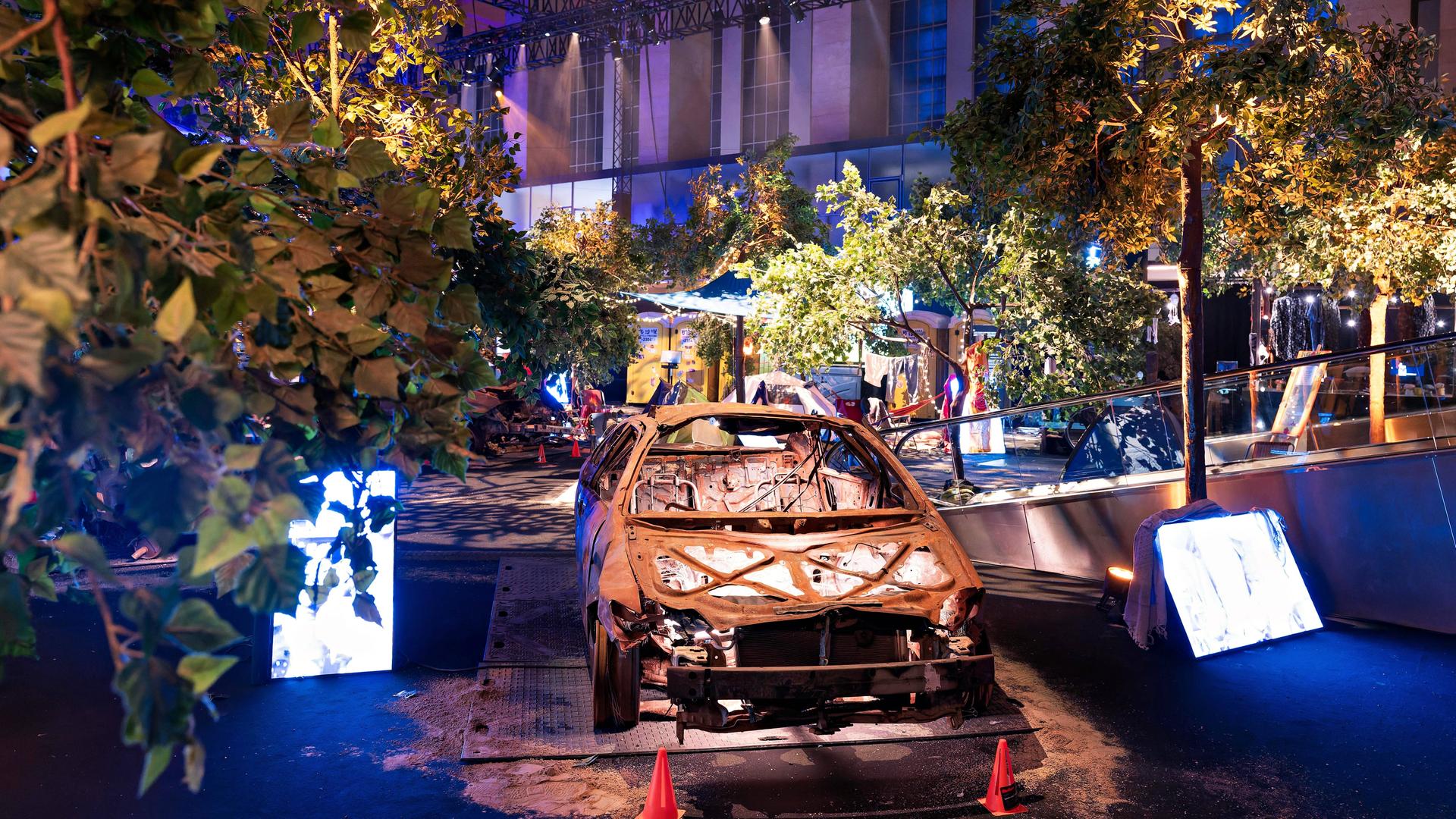 Einblick in die Nova-Festival-Ausstellung in Berlin: In gedämpfter Lichtstimmung ist ein ausgebranntes Auto zu sehen