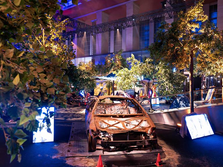 Einblick in die Nova-Festival-Ausstellung in Berlin: In gedämpfter Lichtstimmung ist ein ausgebranntes Auto zu sehen