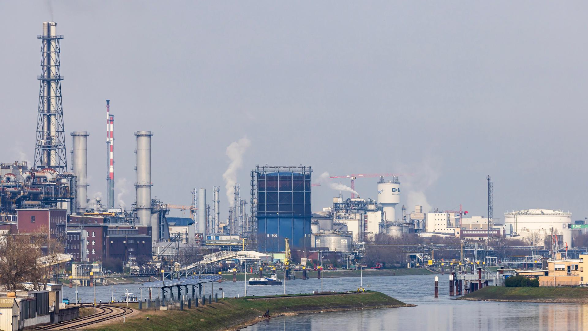 Am Rhein in Ludwigshafen sind Industrieanlagen und rauchende Schornsteine zu sehen. 