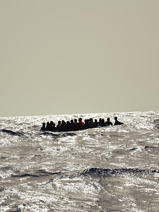 Ein Holzboot mit etwa 30 Menschen versucht bei hohen Wellengang die gefährliche Überfahrt nach Italien. Oft geraten diese labilen und überfüllten Boote in Seenot.