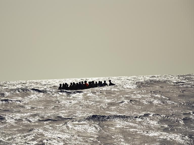 Ein Holzboot mit etwa 30 Menschen versucht bei hohen Wellengang die gefährliche Überfahrt nach Italien. Oft geraten diese labilen und überfüllten Boote in Seenot.