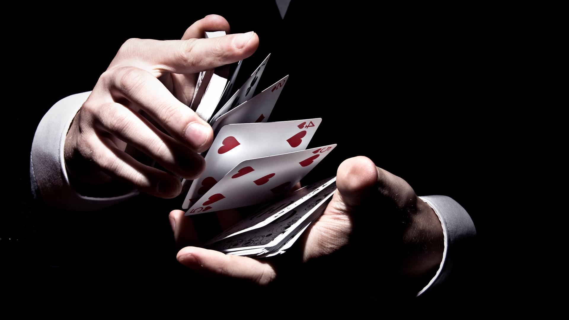 Kartentrick eines Zauberers. Zwischen zwei Händen fliegen Karten eines Kartenspiels