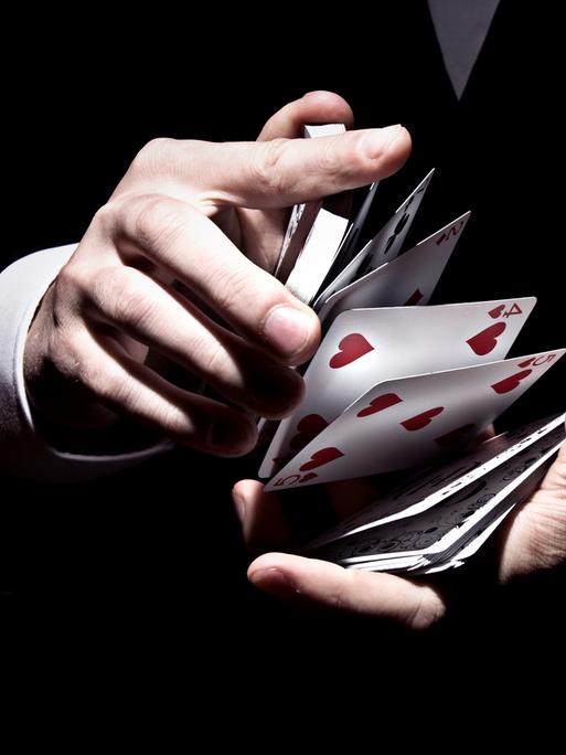 Kartentrick eines Zauberers. Zwischen zwei Händen fliegen Karten eines Kartenspiels