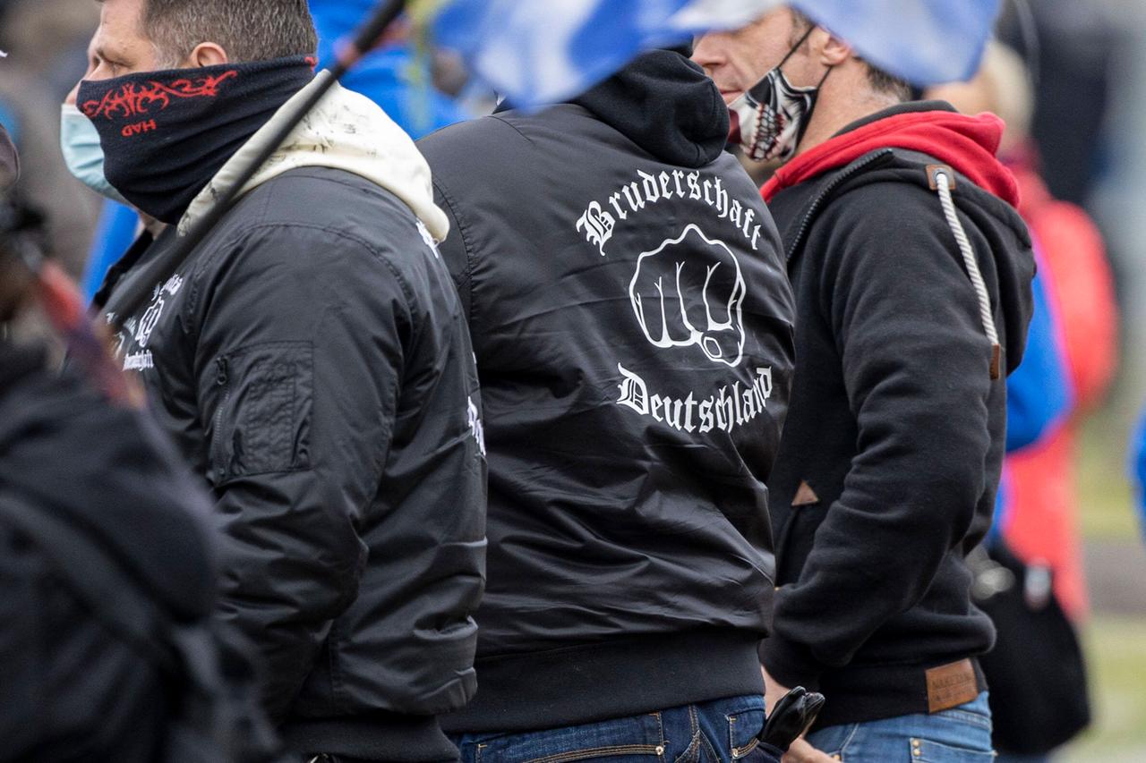 Rechtsextreme bei einer Querdenken-Demo. Einer trägt eine Jacke mit der Aufschrift Bruderschaft Deutschland.