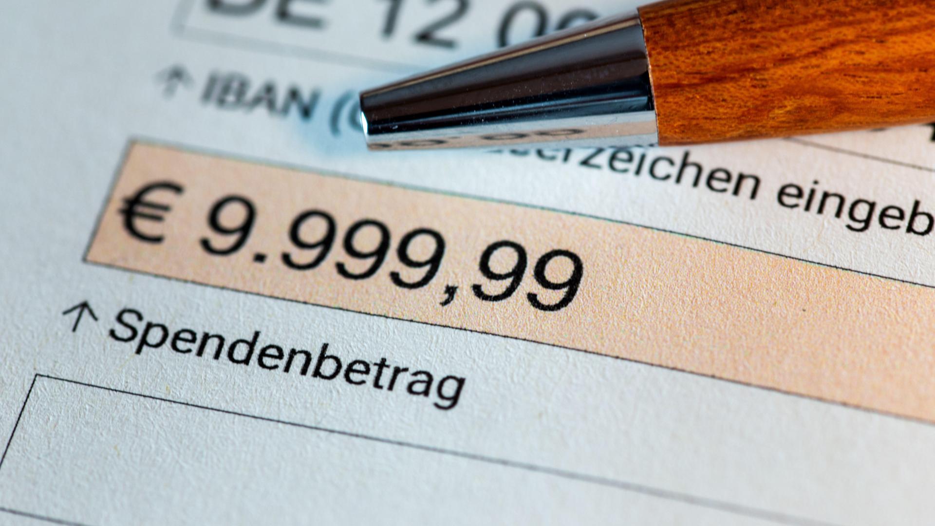 Symbolbild Parteispende: Ein Kugelschreiber liegt auf einem Überweisungsformular. Darin ist die Summe 9.999,99 Euro aufgeführt. 