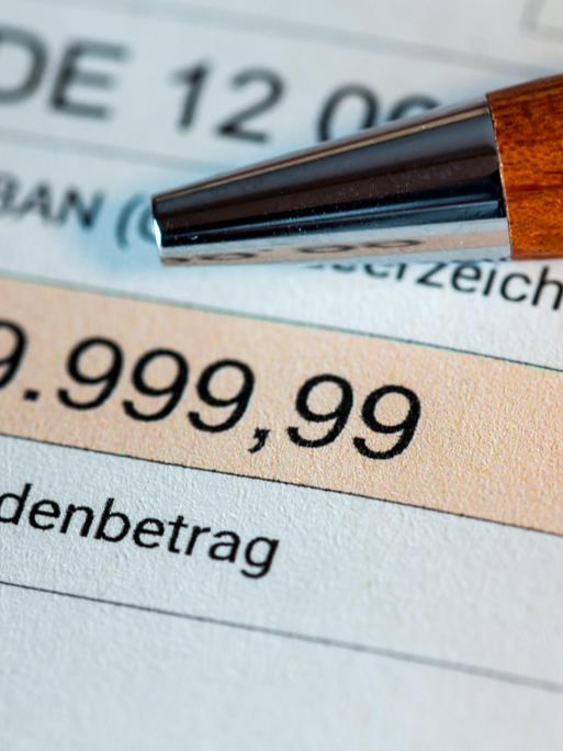 Symbolbild Parteispende: Ein Kugelschreiber liegt auf einem Überweisungsformular. Darin ist die Summe 9.999,99 Euro aufgeführt. 