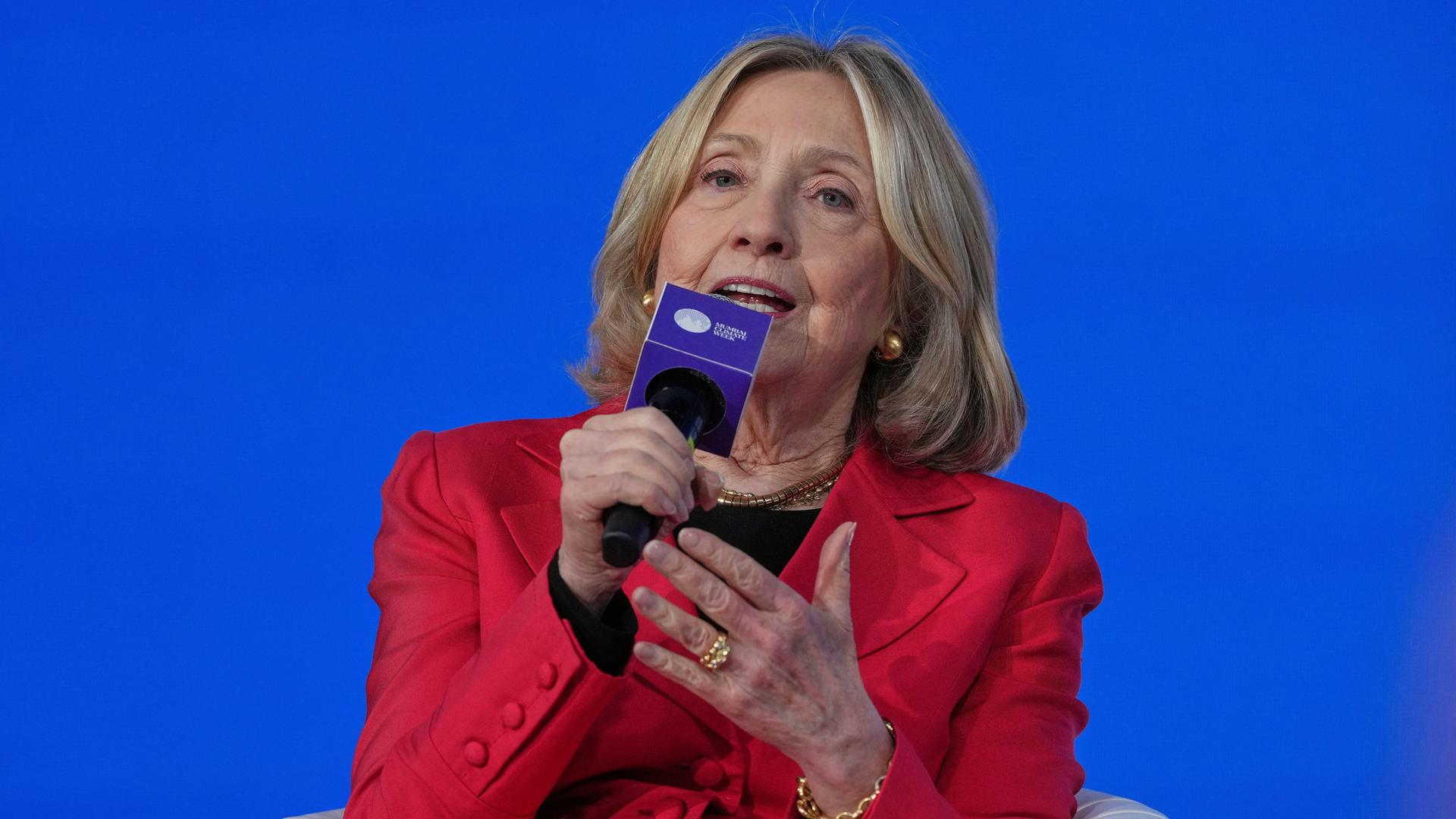 Hillary Clinton spricht in ein Mikrofon, das sie in der rechten Hand hält.
