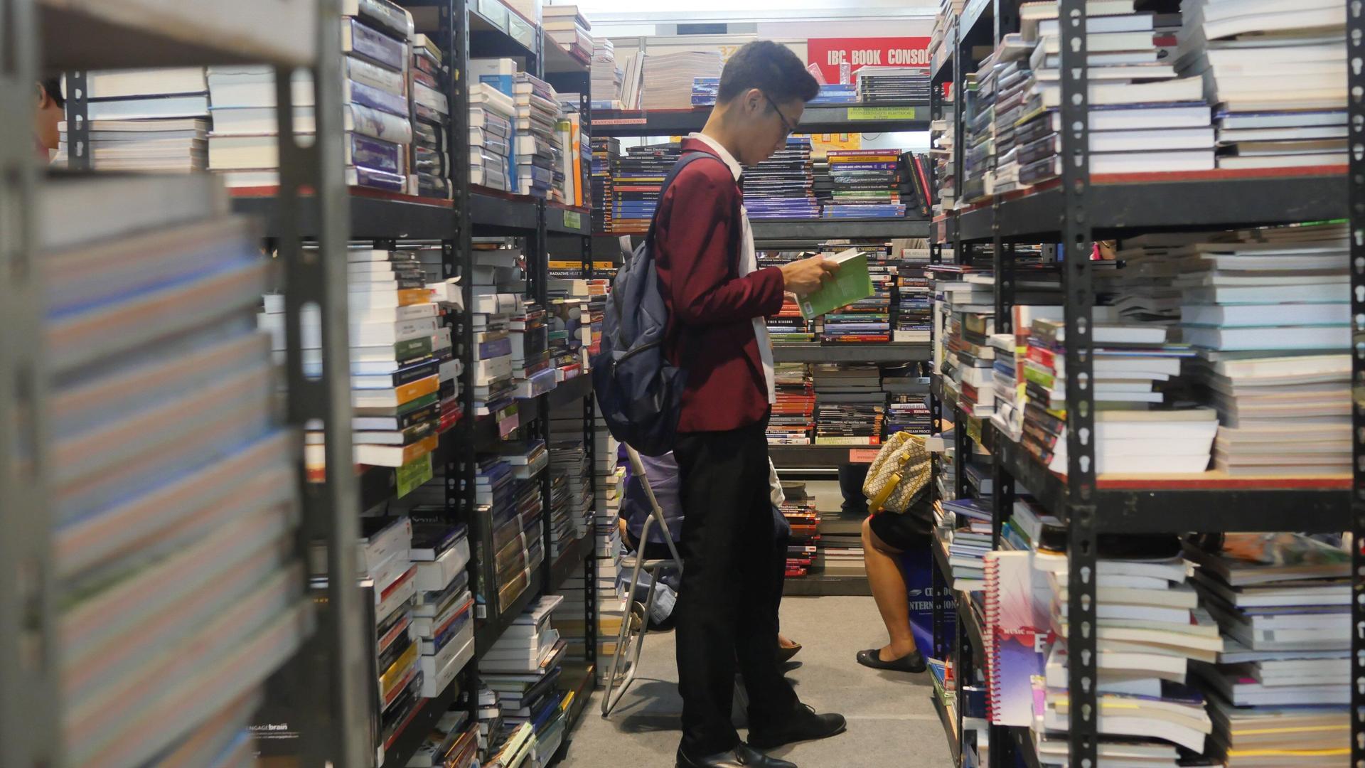Ein Mann liest in einer Buchhandlung ein Buch - auf der 37. Internationalen Buchmesse in Manila Ein Mann liest in einer Buchhandlung ein Buch - auf der 37. Internationalen Buchmesse in Manila
