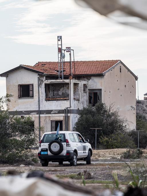 Ein UN Fahrzeug passiert eine verlassenes Haus innerhalb der Pufferzone. Die türkische Armee installierte die Flagge der Türkei und der so genannten "Türkischen Republik Nordzypern" auf dem Dach eines verlassenen Hauses, das als "Haus von Christalla" bekannt wurde.