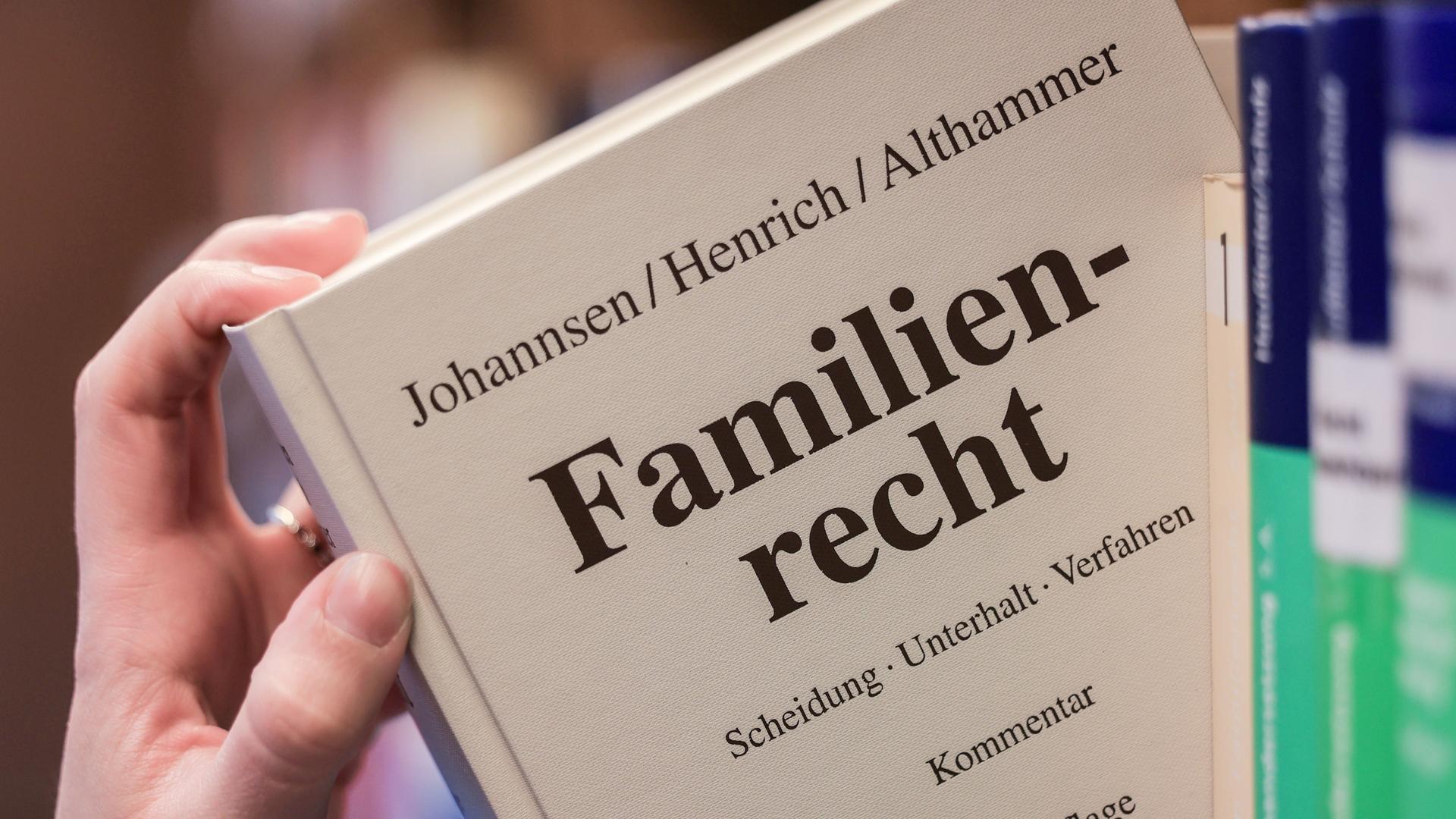 Eine Juristin nimmt den Gesetzestext zum Familienrecht aus dem Regal