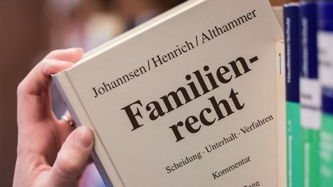 Eine Juristin nimmt den Gesetzestext zum Familienrecht aus dem Regal
