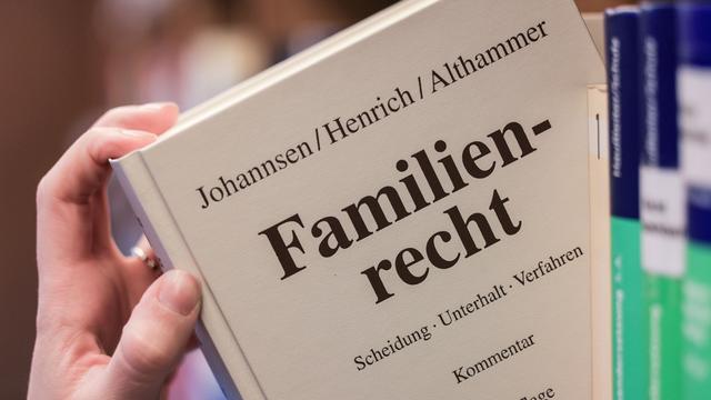 Eine Juristin nimmt den Gesetzestext zum Familienrecht aus dem Regal Eine Juristin nimmt den Gesetzestext zum Familienrecht aus dem Regal