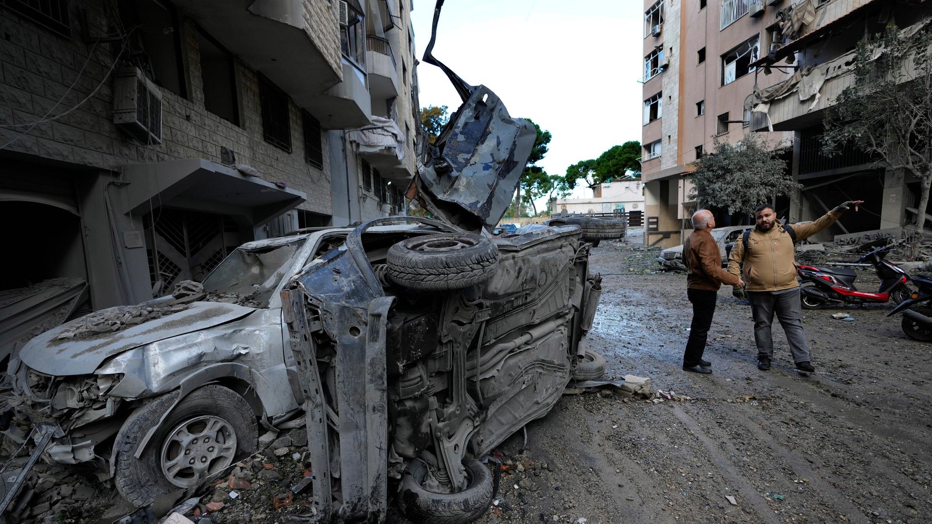 Anwohner stehen in der Nähe von Autos, die nach dem israelischen Luftangriff in Dahieh, einem südlichen Vorort von Beirut, Libanon, zerstört wurden. 