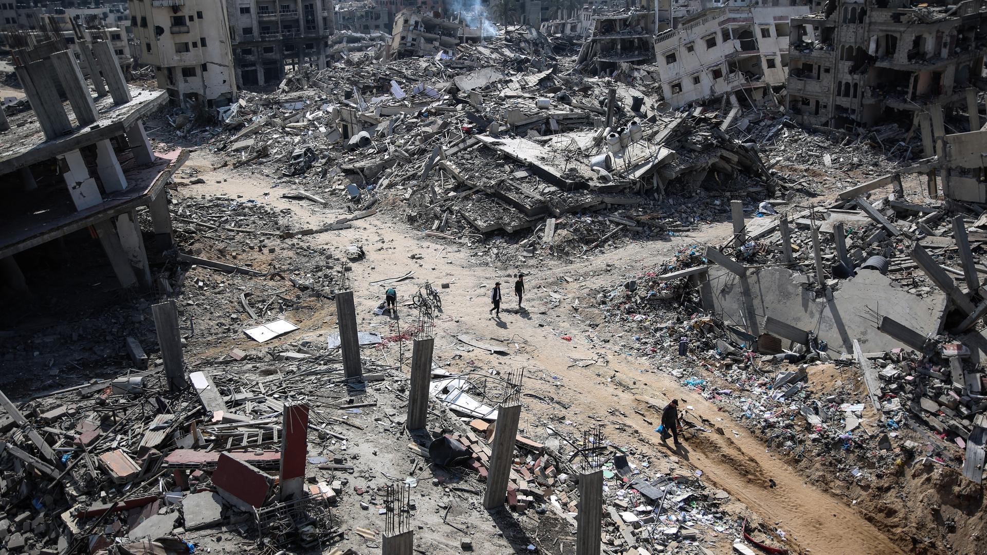 Palästinenser laufen nach einem Bombenangriff durch Ruinen.