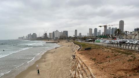 Die Küstenpromenade von Tel Aviv. Hinter dem Strand sieht man viele Hochhäuser. 
