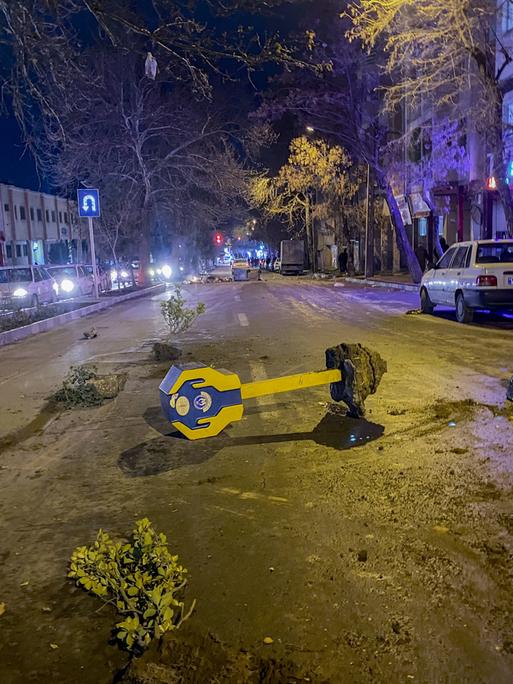 Steine, Äste und eine umgestürzte Spendenbox liegen während Unruhen im iranischen Hamedan auf einer Straße. Es handelt derzeit um die größten Proteste in der Islamischen Republik seit drei Jahren.