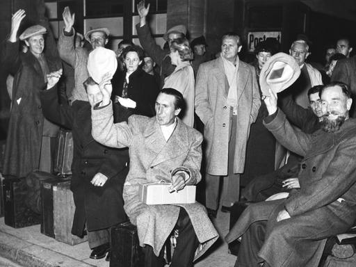 Schwarz-Weiß-Aufnahme einer Gruppe von Heimkehrern vor dem Bahnhof Zoo in Berlin