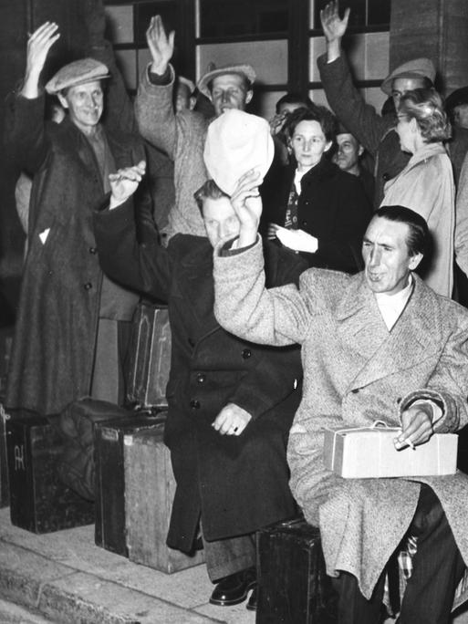 Schwarz-Weiß-Aufnahme einer Gruppe von Heimkehrern vor dem Bahnhof Zoo in Berlin