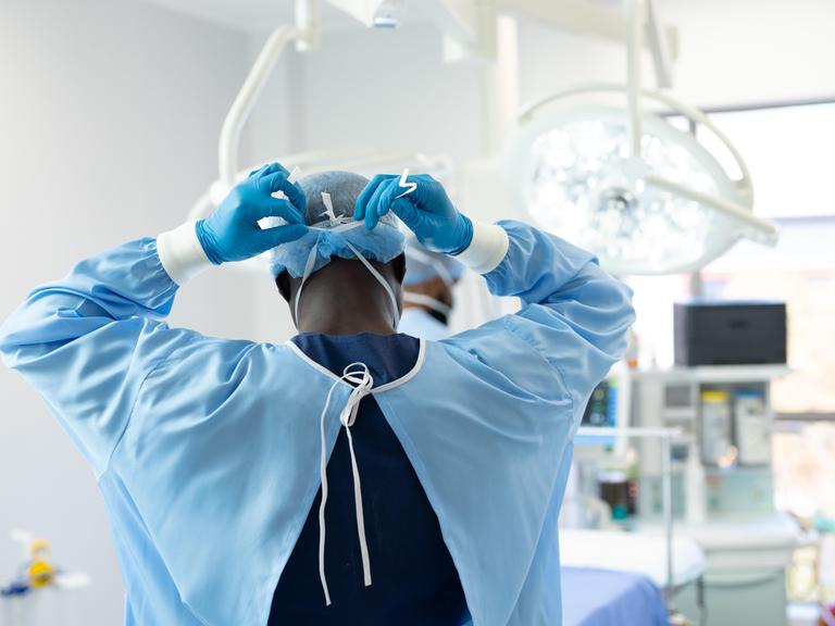 Ein Arzt zieht sich Operationskleidung im OP an.