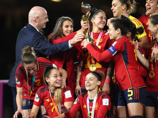 FIFA-Präsident Infatino hält gemeinsam mit einigen Spielerinnerin des spanischen Fußball-WM-Teams den Pokal