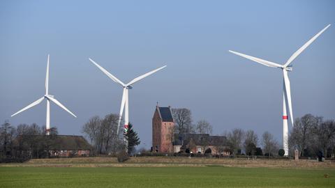 Blick auf das Dorf Klixbüll in Nordfriesland in Schleswig-Holstein: Die St.-Nikolaus-Kirche ist umgeben von drei Windrädern. 