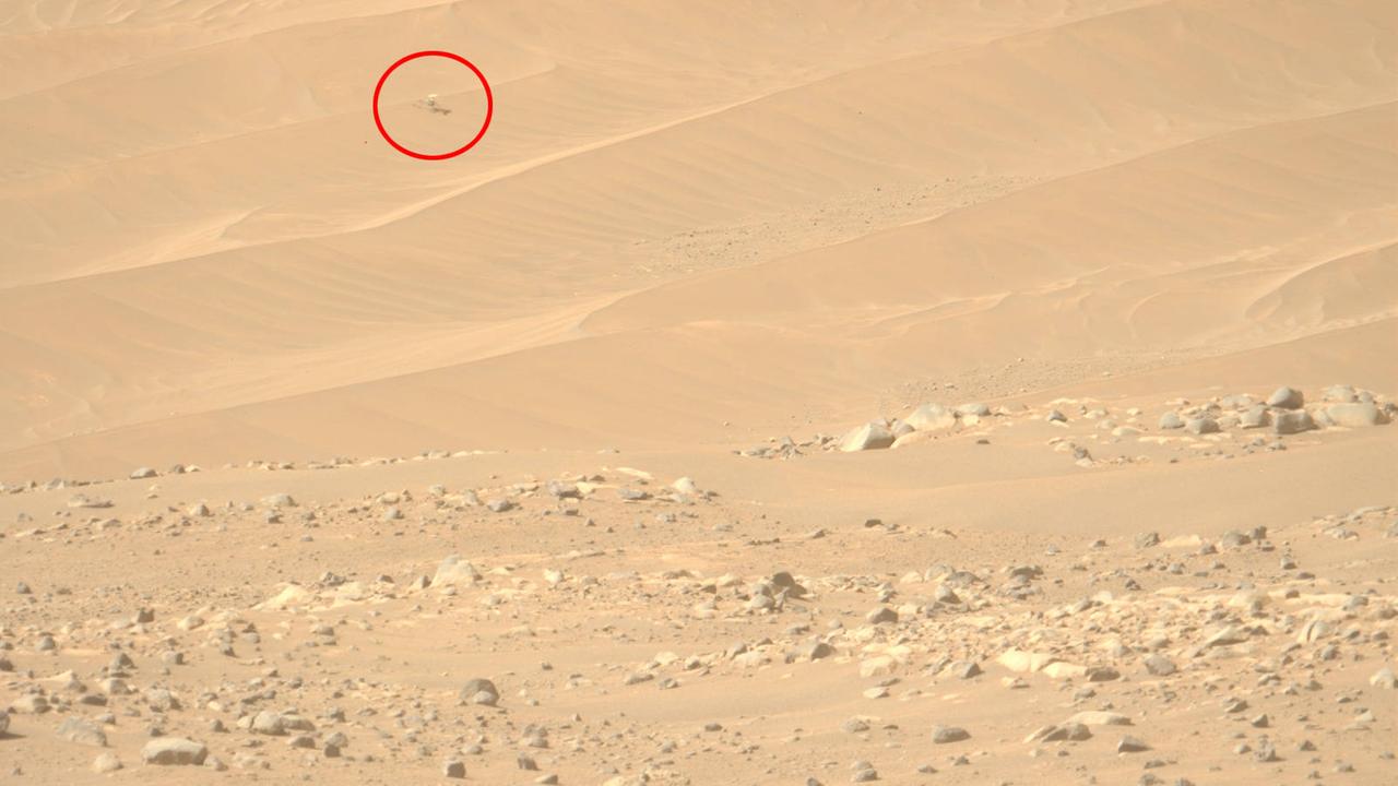 Ein Bild der Mars-Oberfläche. Als kleiner Punkt ist am oberen Bildrand - rot eingekreist - der Mini-Hubschrauber "Ingenuity" zu sehen.