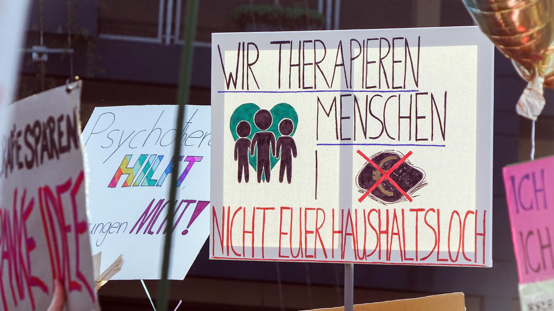 Ein Transparent mit der Aufschrift: "Wir therapien Menschen, nicht euer Haushaltsloch" auf einer Demonstration gegen Honorarkürzungen in der Psychotherapie am 19. März 2026 in Düsseldorf.