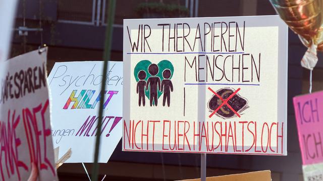 Ein Transparent mit der Aufschrift: "Wir therapien Menschen, nicht euer Haushaltsloch" auf einer Demonstration gegen Honorarkürzungen in der Psychotherapie am 19. März 2026 in Düsseldorf.