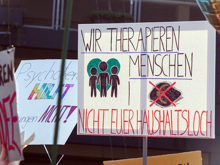 Ein Transparent mit der Aufschrift: "Wir therapien Menschen, nicht euer Haushaltsloch" auf einer Demonstration gegen Honorarkürzungen in der Psychotherapie am 19. März 2026 in Düsseldorf.
