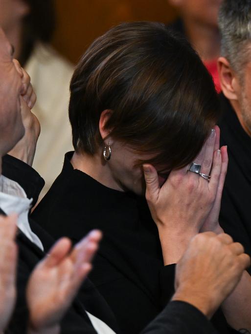Die Schweizer Autorin Dorothee Elmiger (M, «Die Holländerinnen») reagiert bei der Bekanntgabe der Gewinnerin des Deutschen Buchpreis 2025 emotional, indem sie ihre Hände vor ihr Gesicht legt. Die Menschen um sie herum klatschen.