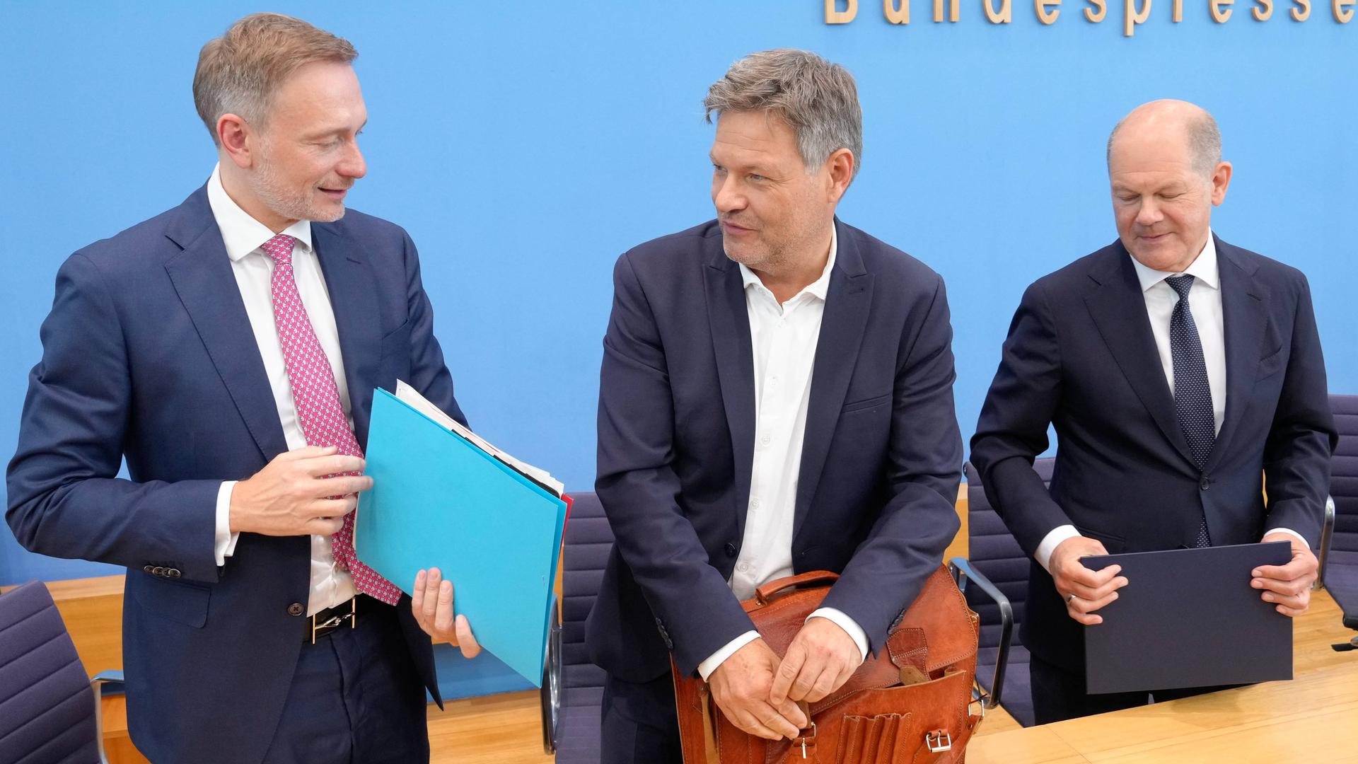 Christian Lindner, Robert Haback und Olaf Scholz stehen hinter einem Tisch und packen ihre Papiere ein.