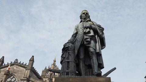 Eine Statue von Adam Smith steht auf einem Sockel, der mit seinem Namen beschriftet ist.