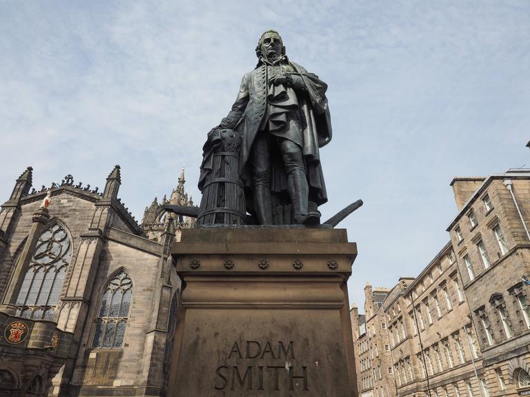 Eine Statue von Adam Smith steht auf einem Sockel, der mit seinem Namen beschriftet ist.